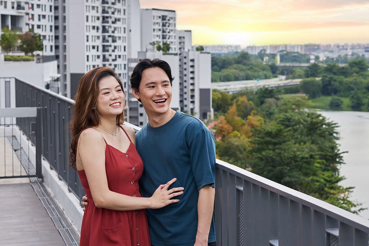 A couple standing on the rooftop garden of an HDB block, looking out at the scenery.
